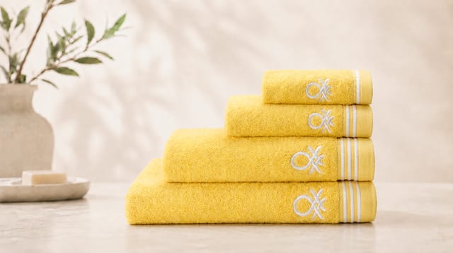 סדרת Classic Benetton, מגבות צהובות מקופלות עם פסים לבנים ולוגו רקום בלבן