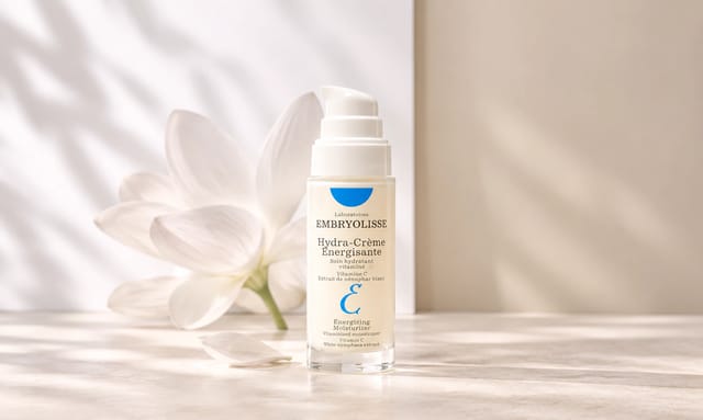 קרם לחות Hydra-Crème Énergisante של המותג Embryolisse, על רקע בהיר ועדין עם פרח לבן ותאורה רכה.