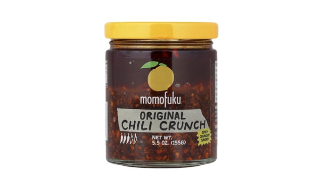 iHerb - צנצנת זכוכית של Momofuku Chili Crunch עם מכסה צהוב, מלאה ברוטב צ'ילי כהה פציח
