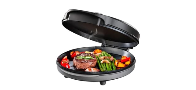 פוד אפיל ANYCOOK - מכשיר בישול עגול שחור פתוח עם סטייק, אספרגוס וירקות צבעוניים על משטח הצלייה